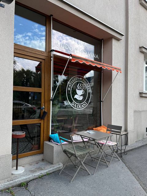 Okno s ponukou sudového vína a stolík na terase pred prevádzkou