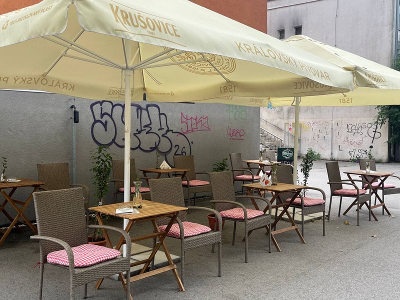 Terasa kaviarničky na Hlinkovej — drevené stolíky, ratanové kreslá a slnečníky